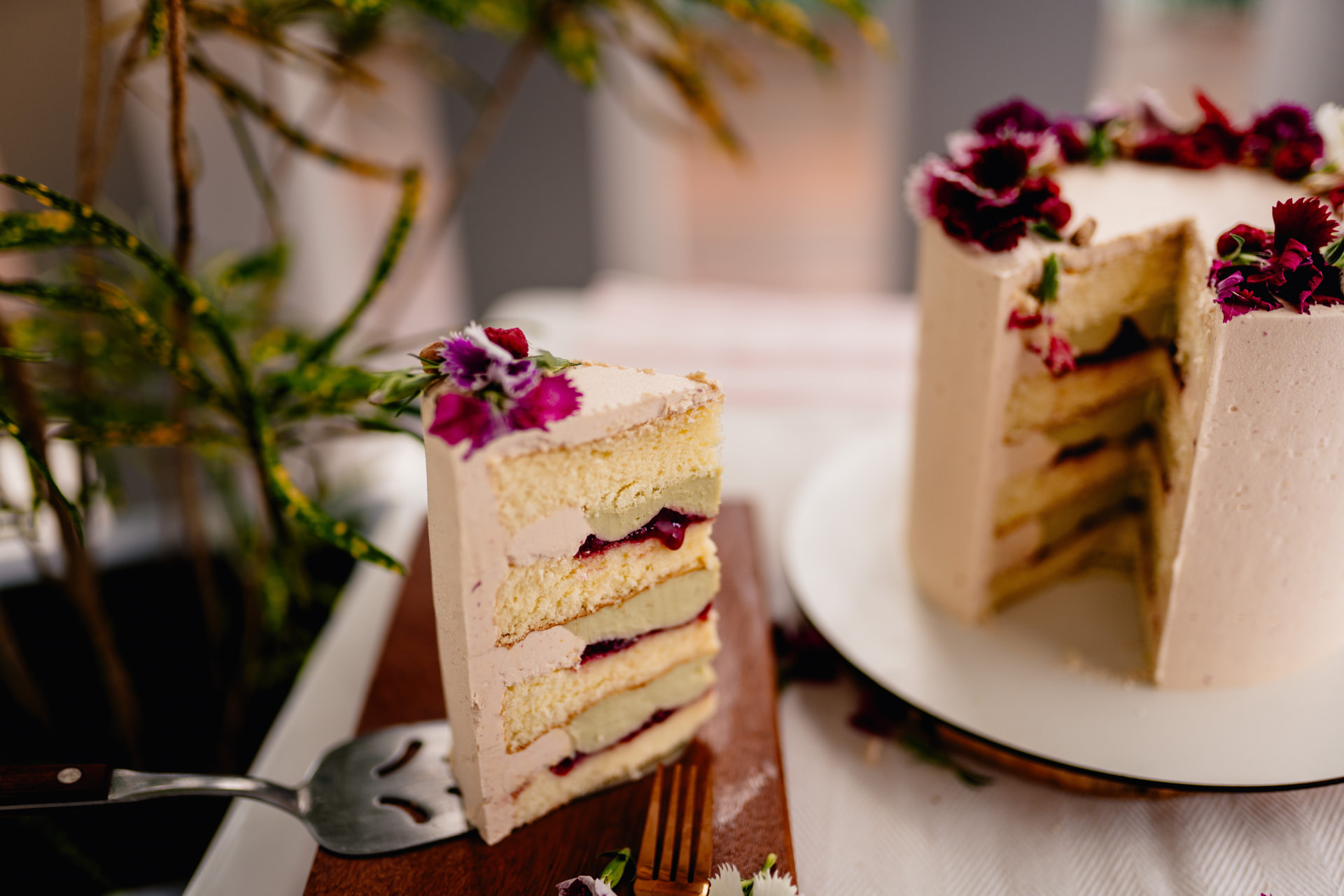 Slice of layer cake with red berry filling and edible flowers